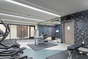a gym with cardio equipment and mirrors